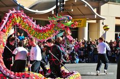 people are walking down the street with colorful dragon kites in their hands and onlookers watching