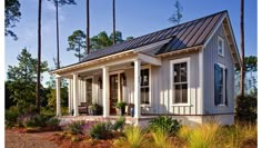 a small white house surrounded by trees and plants