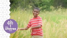 a young boy is standing in tall grass