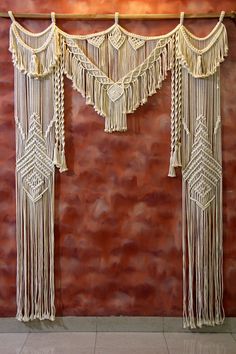 the wall is decorated with white macrame and tassels hanging from it's sides