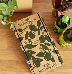 an open book sitting on top of a wooden table next to two bottles and a potted plant