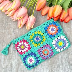 a crocheted purse next to flowers and tulips on a table with a green tassel