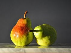 two pears sitting side by side on a counter top, one is green and the other is red