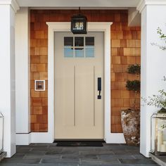 a white front door with two lanterns on each side and an open window above it