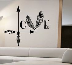 an arrow with two feathers and the word love on it is next to a white couch