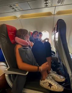 some people sitting on an airplane with their feet up and one person holding a baby