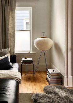 a living room filled with furniture and a lamp on top of a wooden floor next to a window