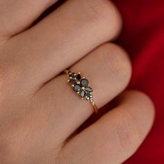 a woman's hand wearing a gold ring with black and white stones on it