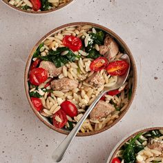 two bowls filled with pasta, meat and veggies on top of a table