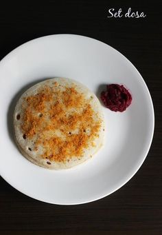 a white plate topped with food on top of a wooden table next to a red sauce