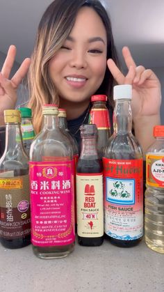 a woman standing in front of many different kinds of bottles with one hand up to the camera