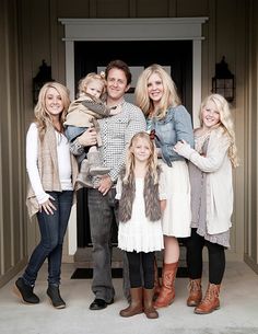 a family posing for a photo in front of a door with their two children and one adult