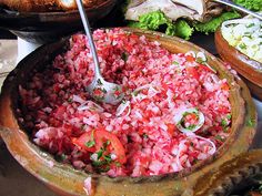 a large wooden bowl filled with chopped red onions and broccoli on top of a table