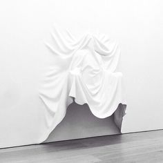 a black and white photo of a sculpture on the floor in front of a wall