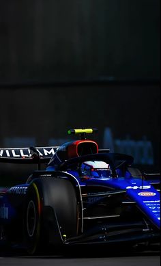 a blue race car driving on a track at night time with the lights turned on