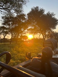 the sun is setting behind two people on their atvs in front of some trees