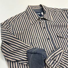 Vintage Wrangler Brushpopper Shirt In Size Large (16-34) Available Now! This Blue And Cream Striped Denim Shirt Is In Like-New Condition And Is Perfect For Anyone Who Loves Vintage Western Wear. Featuring Classic Western Details Such As Snap Buttons And A Western Yoke, This Shirt Is Both Stylish And Durable. Details: Brand: Wrangler Size: Large 16-34 Color: Blue & Cream Material: Denim Condition: Like New, With No Signs Of Wear Add A Piece Of Western History To Your Wardrobe With This Unique And Well-Preserved Shirt. Grab It For $180 Today! Vintage Denim Shirt Outfit, Vintage Wrangler Shirt, Vintage Relaxed Fit Shirt For Rodeo, Denim Blue Long Sleeve Shirt For Rodeo, Long Sleeve Denim Blue Shirt For Rodeo, Dark Wash Long Sleeve Shirt For Rodeo, Denim Blue Button-up Shirt For Rodeo, Western Style Denim Blue Cotton Shirt, Dark Wash Cotton Tops For Rodeo