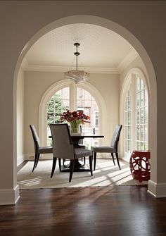 an archway leading into a dining room with chairs and a table in the foreground