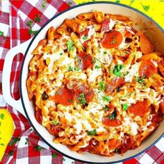 a pasta dish with pepperoni and cheese in a skillet on a checkered table cloth