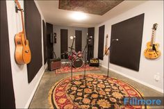 a music studio with guitars and amps on the wall, carpeted flooring