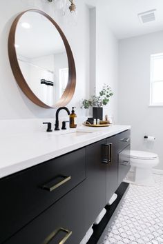 a white and black bathroom with a round mirror