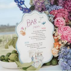 there is a sign that says bar menu next to some flowers and fruit on the table