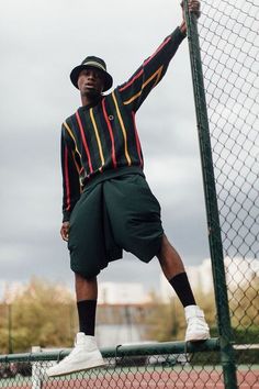 a man holding a tennis racquet on top of a tennis court next to a fence