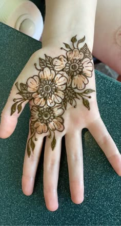 a woman's hand with henna tattoos on her palm and flowers painted on it