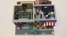 a lego model of a house being held up by a person's hand on top of the floor