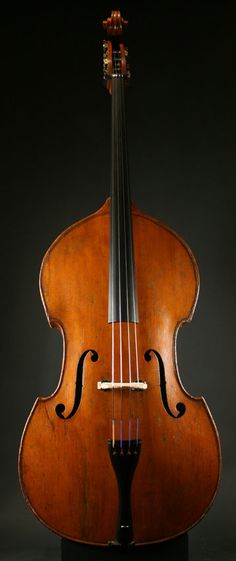 an old violin sitting on top of a black table next to it's back end