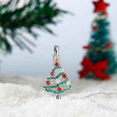 Celebrate the season any time of year with this shimmering Christmas tree pendant. Beautifully handcrafted in sterling silver, this pendant features an evergreen - decorated with alluring enhanced green stones, red stones, and white stones - that features a gold-tone silver star on the top. A festive look that will go with any outfit, this Christmas tree necklace will be a lovely gift for her this season!Carat Weight: 0.89 ctStone Size: 2.4,1,1.2 mmStone Type: Jeulia® StoneNumber of Stones: 44 S Christmas Holiday Green Jewelry, Green Christmas Holiday Jewelry, Green Sparkling Stones Necklace For Gift, Green Christmas Jewelry For Festive Occasion, Silver Christmas Holiday Jewelry, Festive Sterling Silver Jewelry For Christmas, Sterling Silver Jewelry For Christmas, Green Festive Jewelry For New Year, Silver Necklace For Christmas Celebration