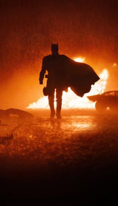 a man in a batman costume is walking through the fire