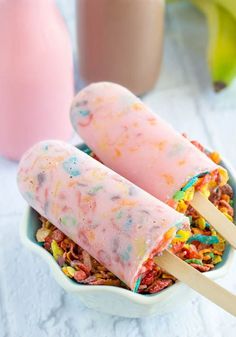 two popsicles with cereal and sprinkles in a bowl