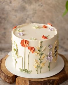 a white cake with orange and purple flowers on it