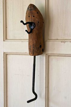 an old fashioned wooden object hanging on a wall with a hook in the shape of a face