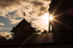 the sun shines brightly behind a building with a roof and steeple on it