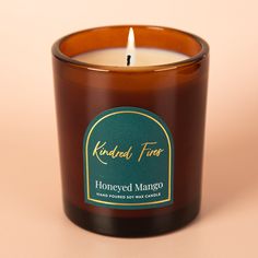 a candle with a label on it sitting in front of a pink background that says, honeyed mango