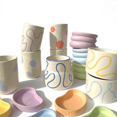 there are many different bowls and cups on the table, all painted in different colors