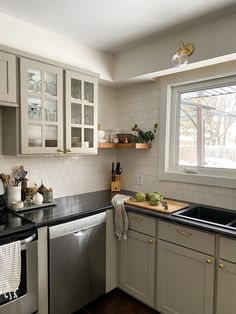 a kitchen with white cabinets and black counter tops is pictured in this image, there are dishes on the dishwasher next to the sink