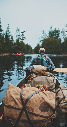 a man in a canoe with two bags on the front, and another bag behind him