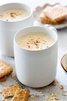 two white mugs filled with milk and crackers