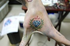 a person's hand with a tattoo on it and a diamond in the middle