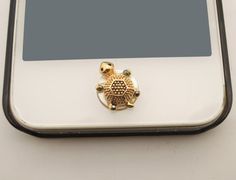 a small gold turtle brooch sitting on top of a white tabletop with a black frame