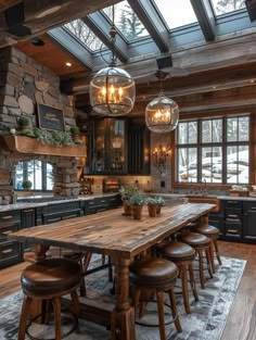 a rustic kitchen with wood floors and black cabinets, an island table surrounded by stools