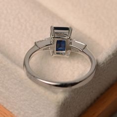 This ring features a 6*8mm emerald cut lab sapphire and sterling silver finished with rhodium. Customization is available. It is made by hand, and it will take about 7 days to finish the ring after your payment is completed. Main stone: Lab sapphire Main stone weight: Approx 1.90 ct Metal type: sterling silver finished with rhodium Accent stone: cz Customization is available, I also can make it with 14k solid gold (white or yellow or rose) and diamond accent stone, just feel free to contact me. Rectangular Lab-created Sapphire Ring For Anniversary, Anniversary Rectangular Lab-created Sapphire Ring, Emerald-cut Sapphire Birthstone Ring, Elegant Rectangular Lab-created Sapphire Rings, Emerald Cut Sapphire Solitaire Promise Ring, Emerald Cut Solitaire Sapphire Promise Ring, Emerald Cut Sapphire Birthstone Ring For Formal Occasions, Emerald Cut Solitaire Sapphire Ring, Fine Jewelry White Gold Square Cut Sapphire Ring