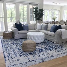 a living room with white couches and blue rugs on the hardwood flooring