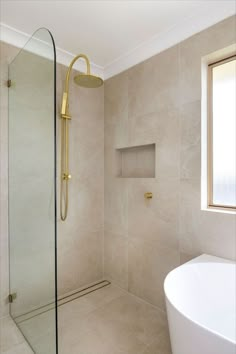 a white bath tub sitting next to a window in a bathroom with beige tile on the walls