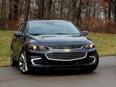 two cars parked side by side on the road in front of some grass and trees