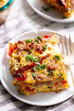 a white plate topped with lasagna covered in cheese and toppings next to a fork