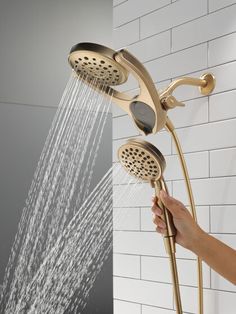 a person is holding the shower head in their hand and spraying it with water from the faucet